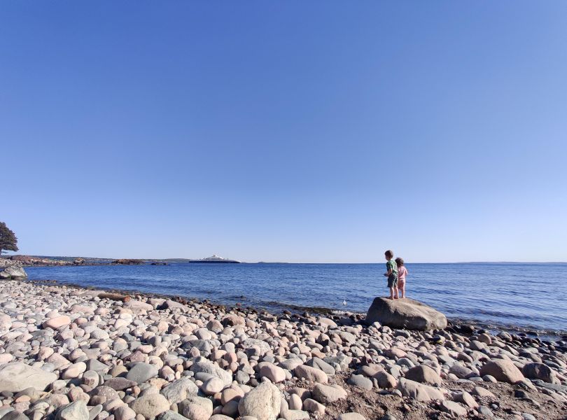 To barn på stor stein ser utover havet